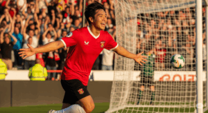 ゴールを決めて最高の笑顔で喜んでいるサッカー選手の写真。
