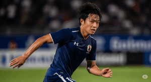 試合終盤、攻守にわたって走り抜き、疲労困憊ながらも闘志あふれる表情を見せる日本人ボランチの写真。
