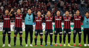 いわきFCの選手たちが、試合後に少し悔しそうな表情で肩を組み、サポーターに挨拶している写真。