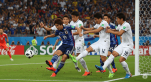 ゴール前の混戦の中、相手DFに囲まれながらも、日本人選手がつま先でボールを押し込むようにトーキックでシュートしている写真。